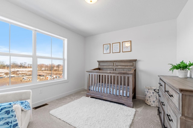 bedroom with baseboards, visible vents, and light colored carpet