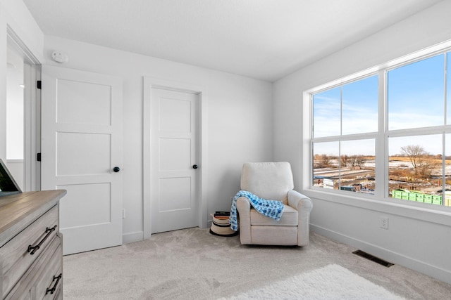 living area featuring baseboards, visible vents, and light colored carpet