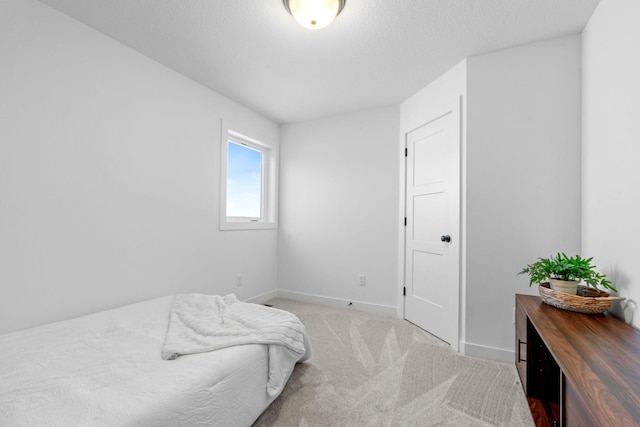 bedroom featuring light carpet, baseboards, and a textured ceiling