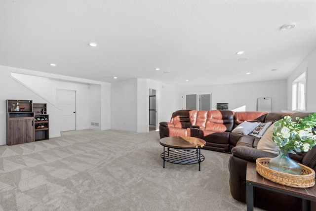 living area featuring a textured ceiling, recessed lighting, visible vents, and light colored carpet