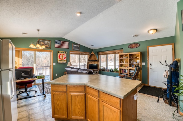 kitchen featuring open floor plan, light countertops, freestanding refrigerator, and a center island