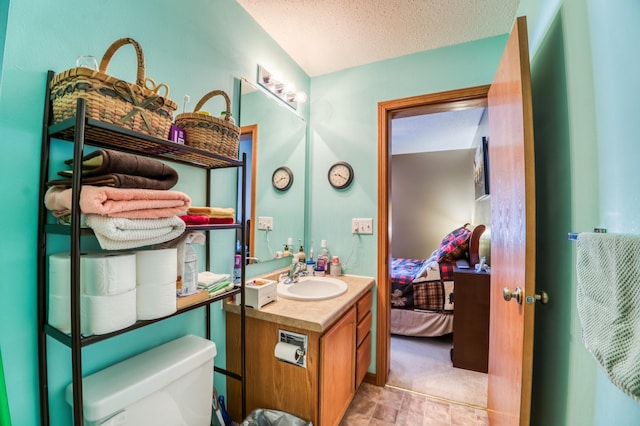 bathroom with ensuite bathroom, a textured ceiling, toilet, and vanity