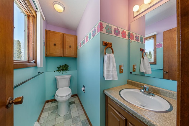 bathroom featuring toilet, tile patterned floors, baseboards, and vanity