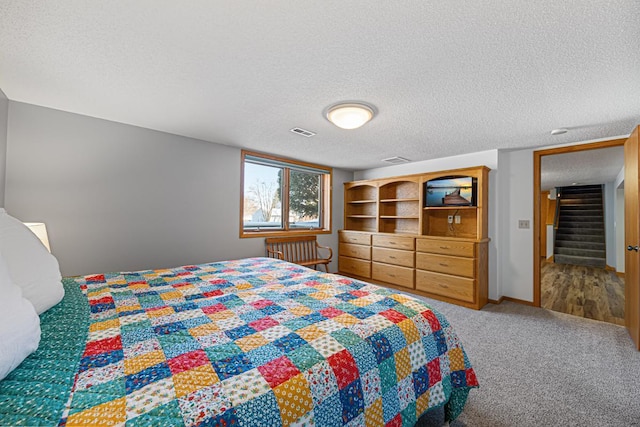 bedroom featuring carpet, visible vents, and a textured ceiling