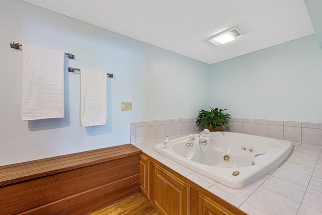 full bathroom featuring visible vents, a textured ceiling, and a whirlpool tub