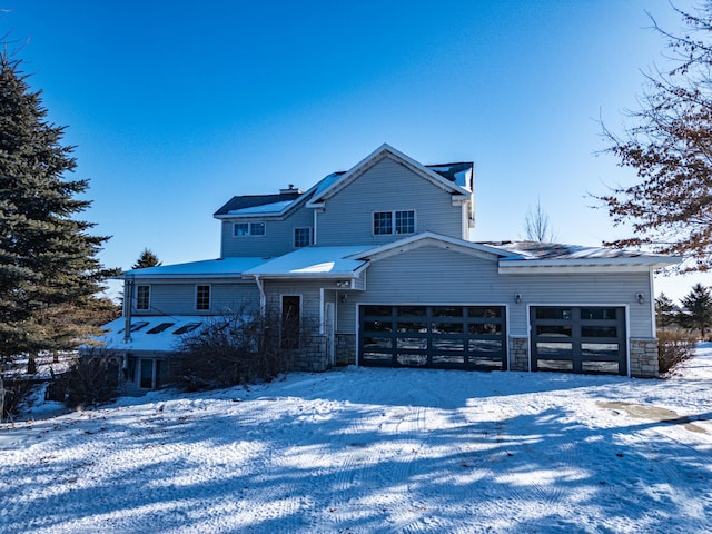 view of front of house with a garage, stone siding, and gravel driveway