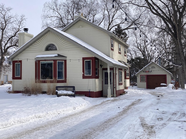 view of front facade with an outbuilding, a chimney, and a detached garage