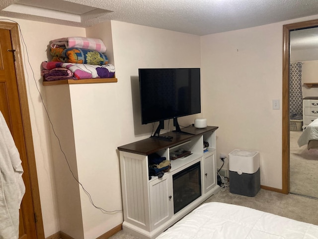 bedroom featuring light carpet, baseboards, and a textured ceiling