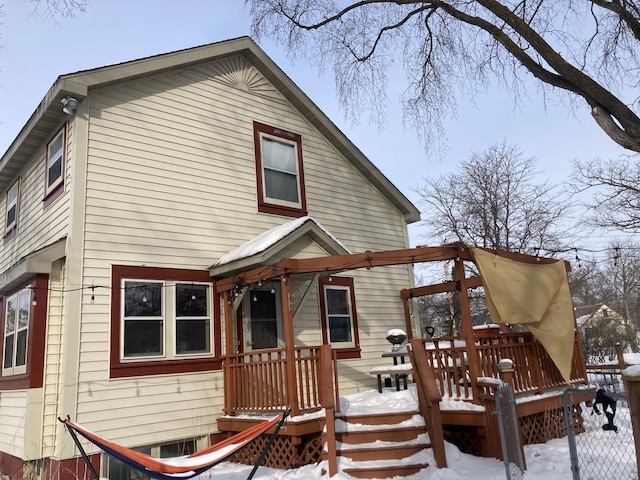 snow covered back of property featuring a wooden deck