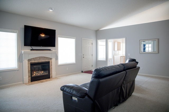 living area with light carpet, vaulted ceiling, plenty of natural light, and a fireplace