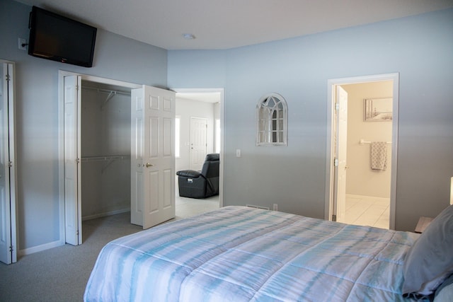 bedroom with a closet, light colored carpet, connected bathroom, and baseboards