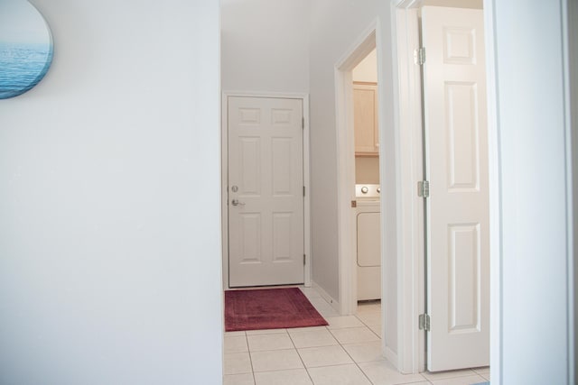 corridor featuring light tile patterned flooring and washer / dryer