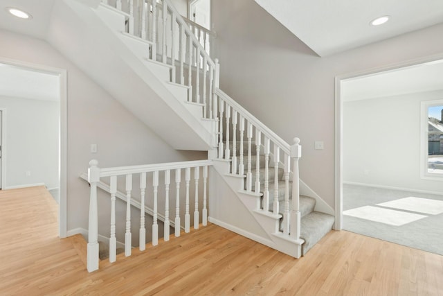 stairs featuring baseboards, wood finished floors, and recessed lighting