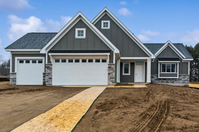 craftsman-style home featuring board and batten siding, stone siding, and driveway