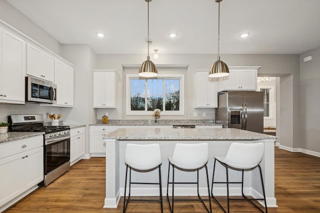 kitchen featuring appliances with stainless steel finishes, a center island, a breakfast bar, and wood finished floors