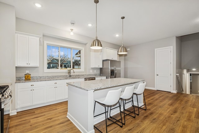 kitchen featuring appliances with stainless steel finishes, light wood-type flooring, a kitchen island, and white cabinets