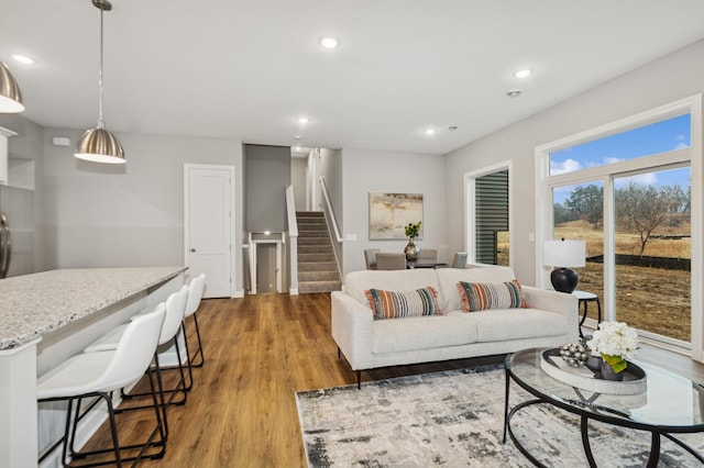 living room with stairs, recessed lighting, and light wood-style floors