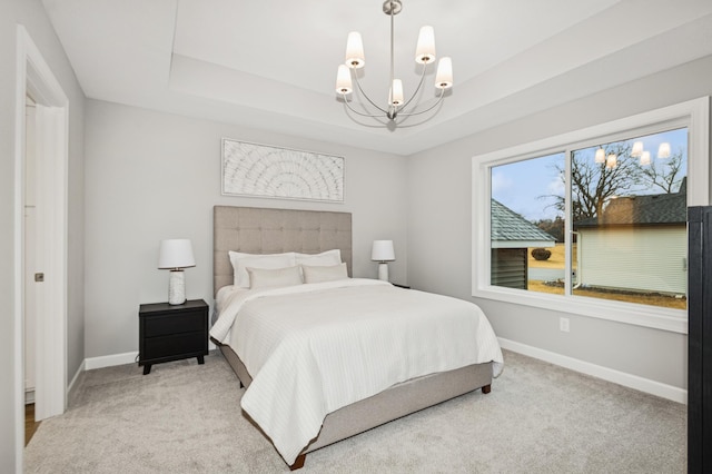 carpeted bedroom featuring baseboards, a raised ceiling, and a notable chandelier