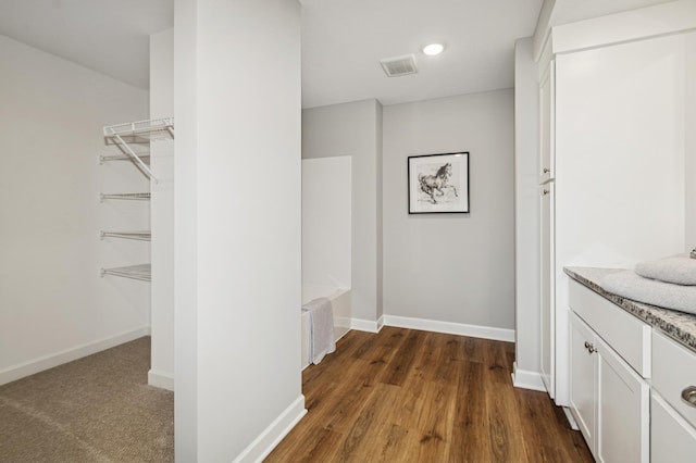 interior space featuring dark wood-style flooring, radiator heating unit, visible vents, and baseboards