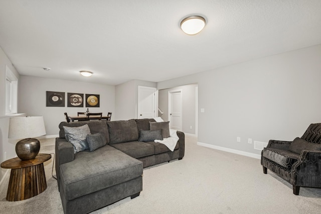 living area featuring carpet, stairs, and baseboards