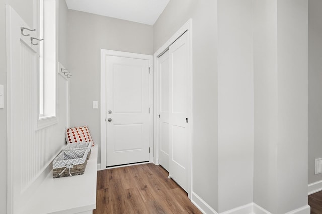 hall featuring wood finished floors, visible vents, and baseboards