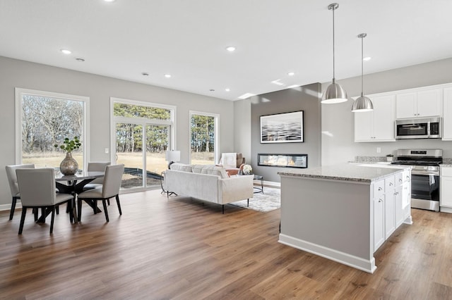 kitchen with a kitchen island, recessed lighting, stainless steel appliances, and wood finished floors