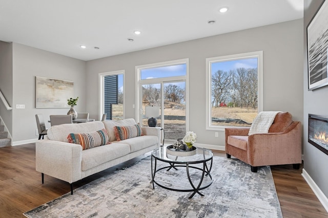 living area featuring baseboards, wood finished floors, and stairs