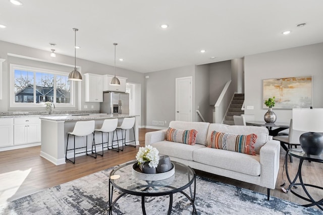 living room with stairway, recessed lighting, light wood-style flooring, and visible vents