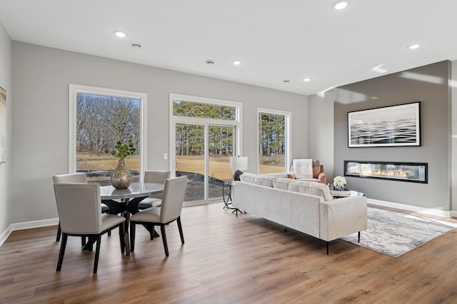 dining room with a glass covered fireplace, recessed lighting, baseboards, and wood finished floors