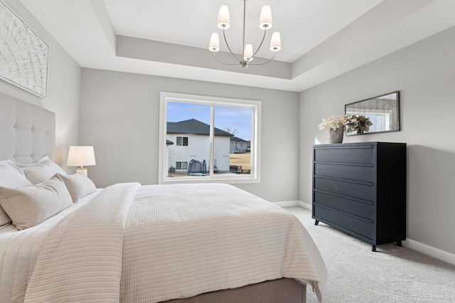 bedroom with a raised ceiling, a notable chandelier, baseboards, and light carpet