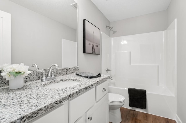 full bathroom featuring visible vents, shower / washtub combination, toilet, wood finished floors, and vanity