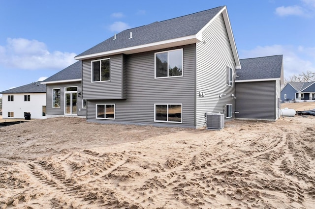 rear view of property featuring central air condition unit and a shingled roof