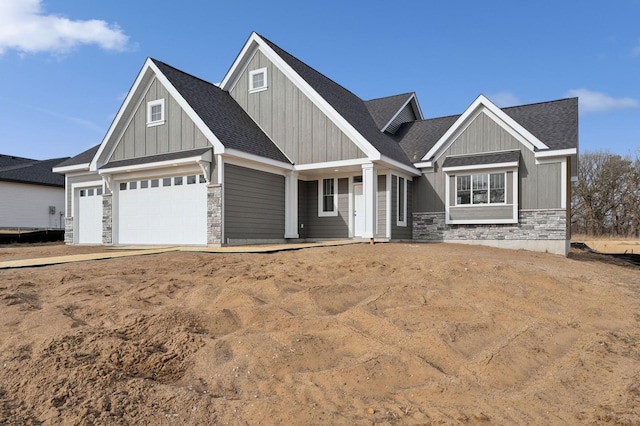 craftsman house with stone siding, board and batten siding, an attached garage, and a shingled roof