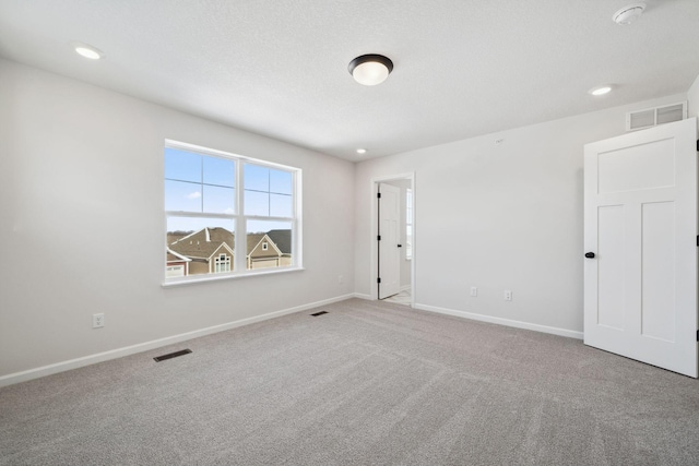 spare room with carpet, baseboards, and visible vents