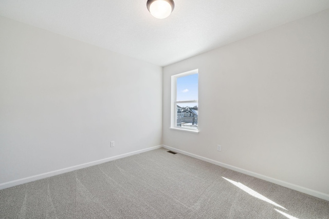 empty room featuring carpet, visible vents, and baseboards