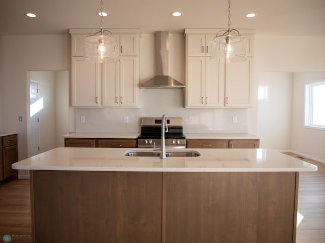 kitchen featuring electric range, a sink, wall chimney range hood, an island with sink, and wood finished floors