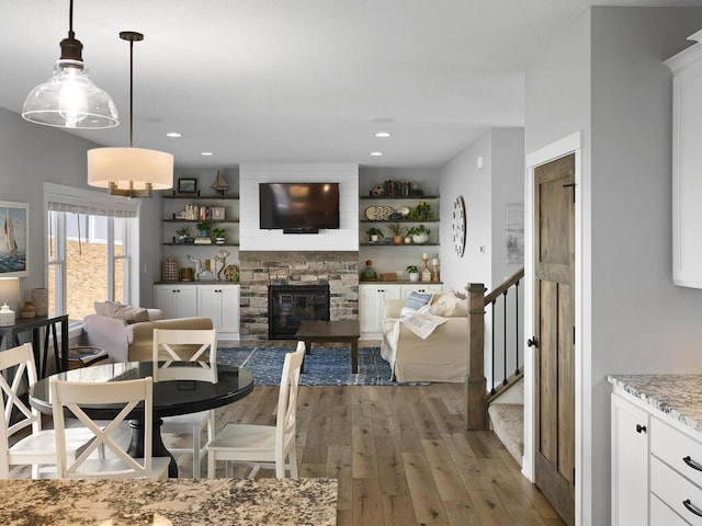 dining room with recessed lighting, stairway, a stone fireplace, and light wood-style flooring