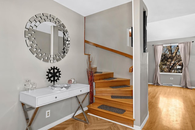 stairs with parquet floors, visible vents, and baseboards