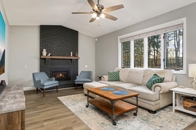 living room with baseboards, lofted ceiling, light wood-style flooring, ceiling fan, and a fireplace