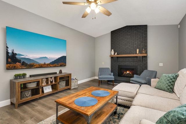 living area with a brick fireplace, vaulted ceiling, baseboards, and wood finished floors