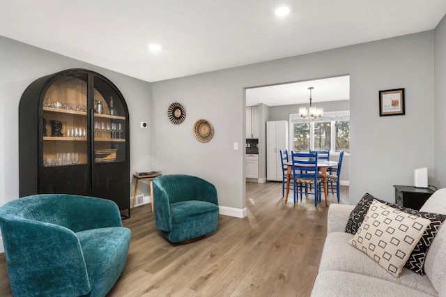 living room featuring a notable chandelier, baseboards, visible vents, and light wood-style floors