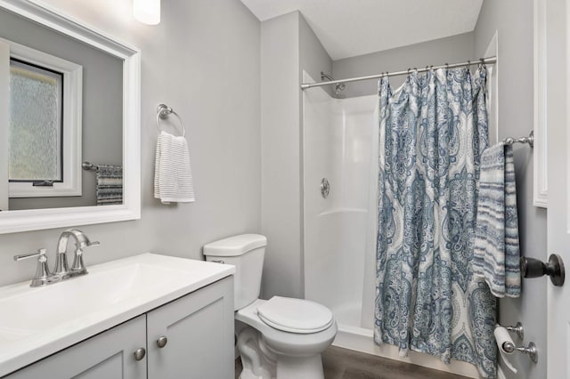 bathroom featuring toilet, a stall shower, wood finished floors, and vanity