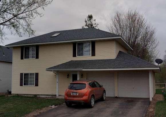 traditional-style home featuring a garage, driveway, and a shingled roof