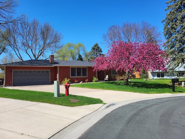 view of front facade with driveway, a front lawn, a chimney, and an attached garage