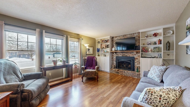 living room featuring a textured ceiling, a fireplace, and wood finished floors