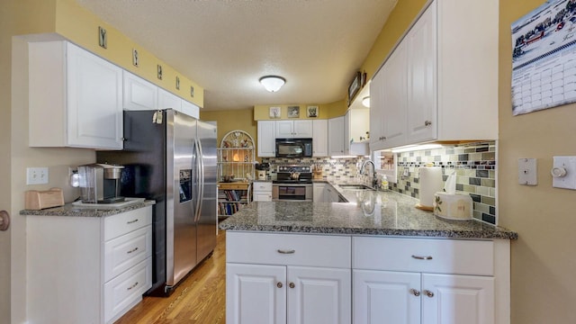 kitchen featuring appliances with stainless steel finishes, white cabinetry, a sink, and backsplash