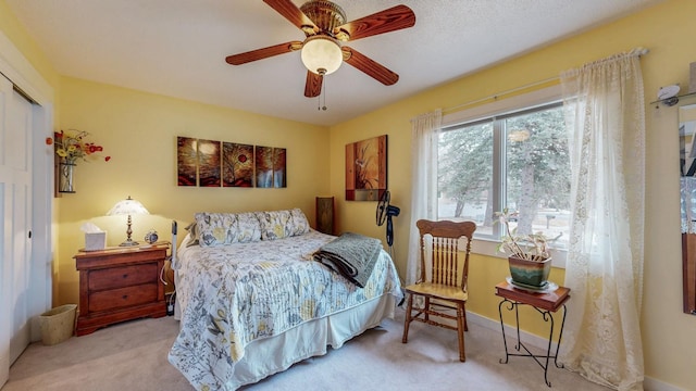 bedroom with baseboards, a closet, a ceiling fan, and light colored carpet