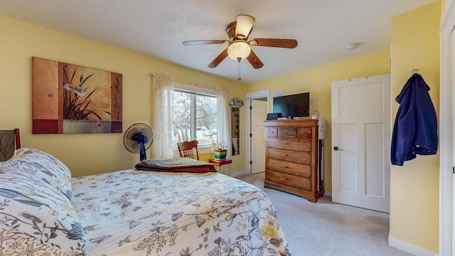 bedroom with light colored carpet, ceiling fan, a textured ceiling, and baseboards