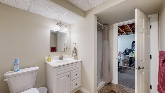 bathroom featuring toilet, a stall shower, baseboards, and vanity