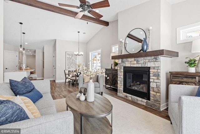 living area featuring a fireplace, wood finished floors, high vaulted ceiling, beamed ceiling, and baseboards